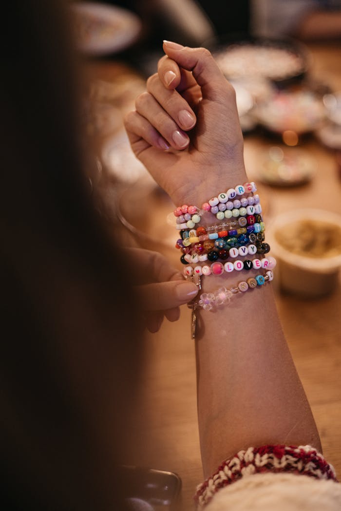Close-up of a wrist adorned with colorful bead bracelets spelling words. Trendy and artistic.